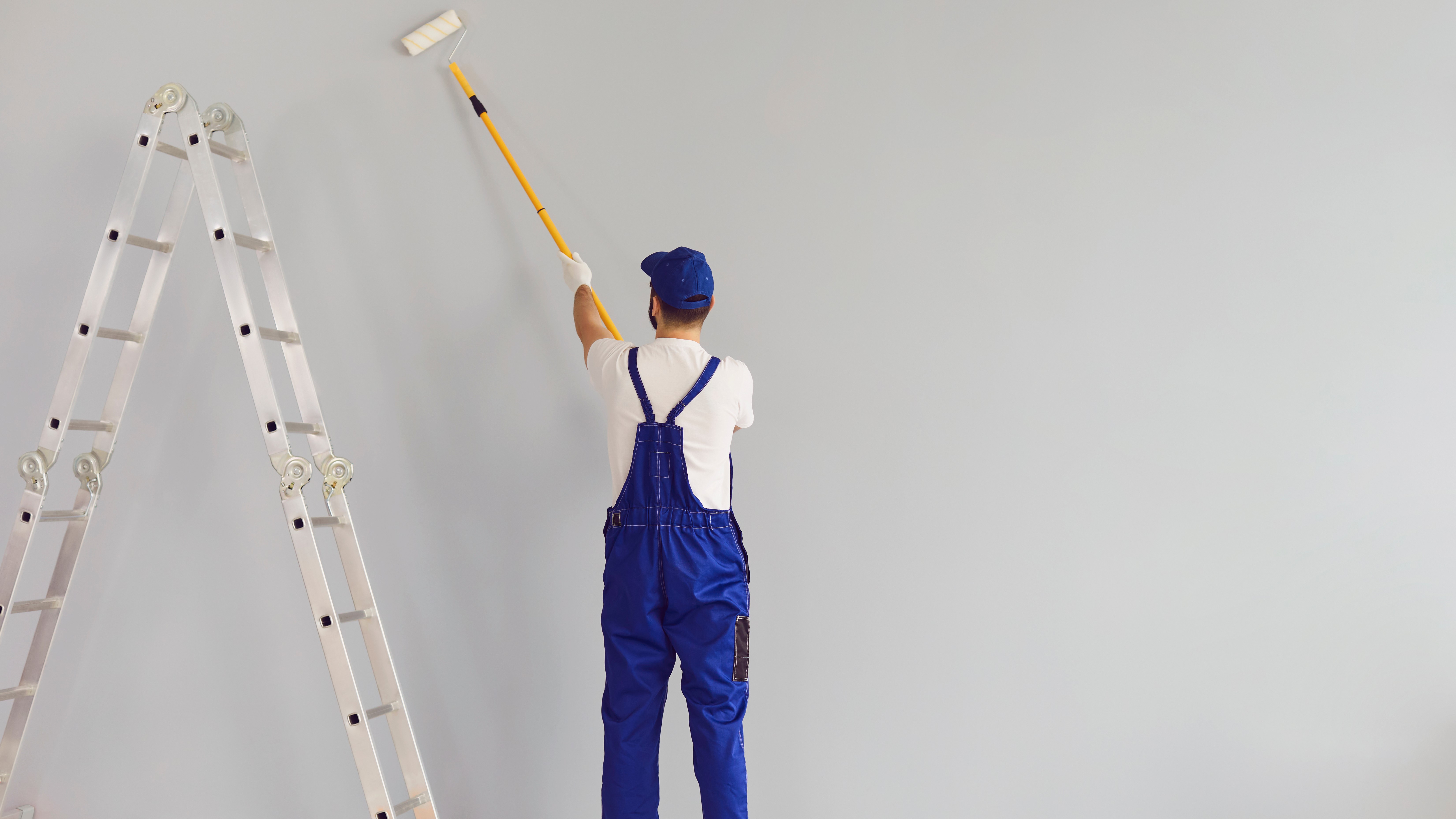 Interior painter finishing painting a gray wall in Washington County home